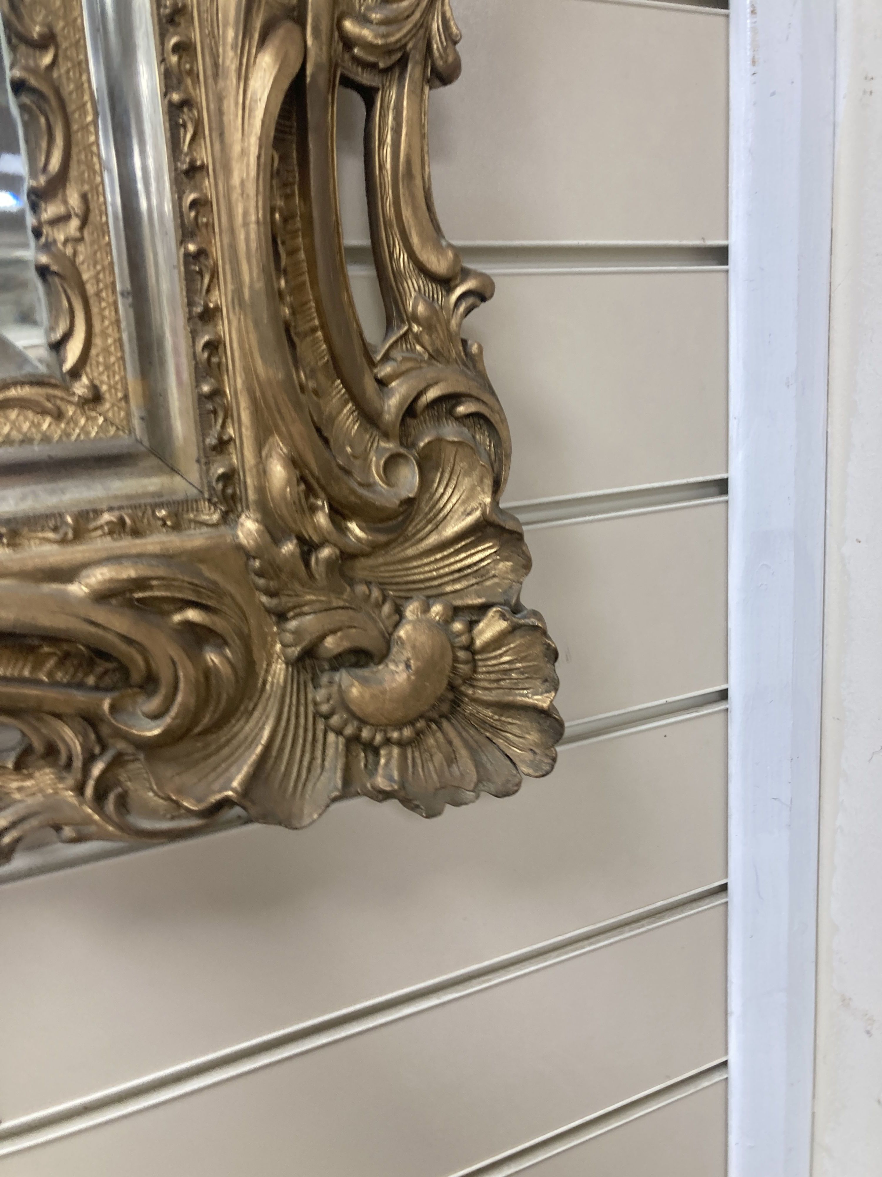 A rectangular carved and pierced framed gilt wall mirror in the rococo style, stepped and moulded border enclosing a bevelled plate, wi